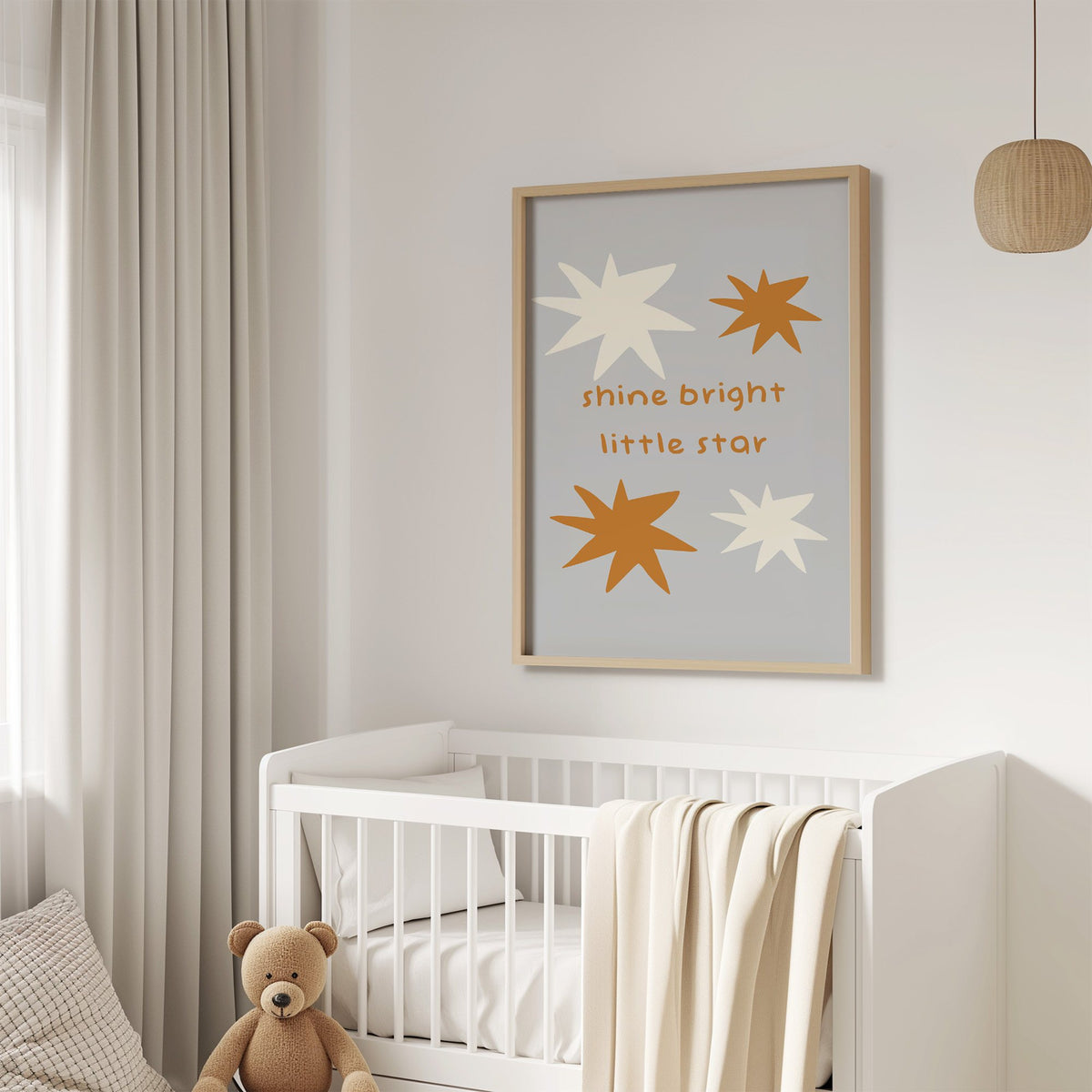 Shine bright little star nursery print in an oak frame above a white crib with a teddy bear