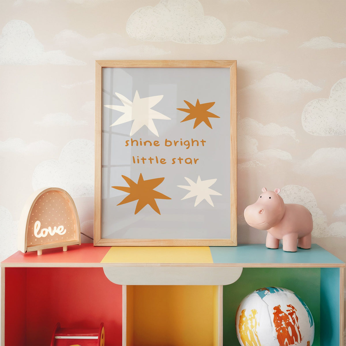 Shine bright little star nursery print in an oak frame on a rainbow toy shelf against cloud wallpaper