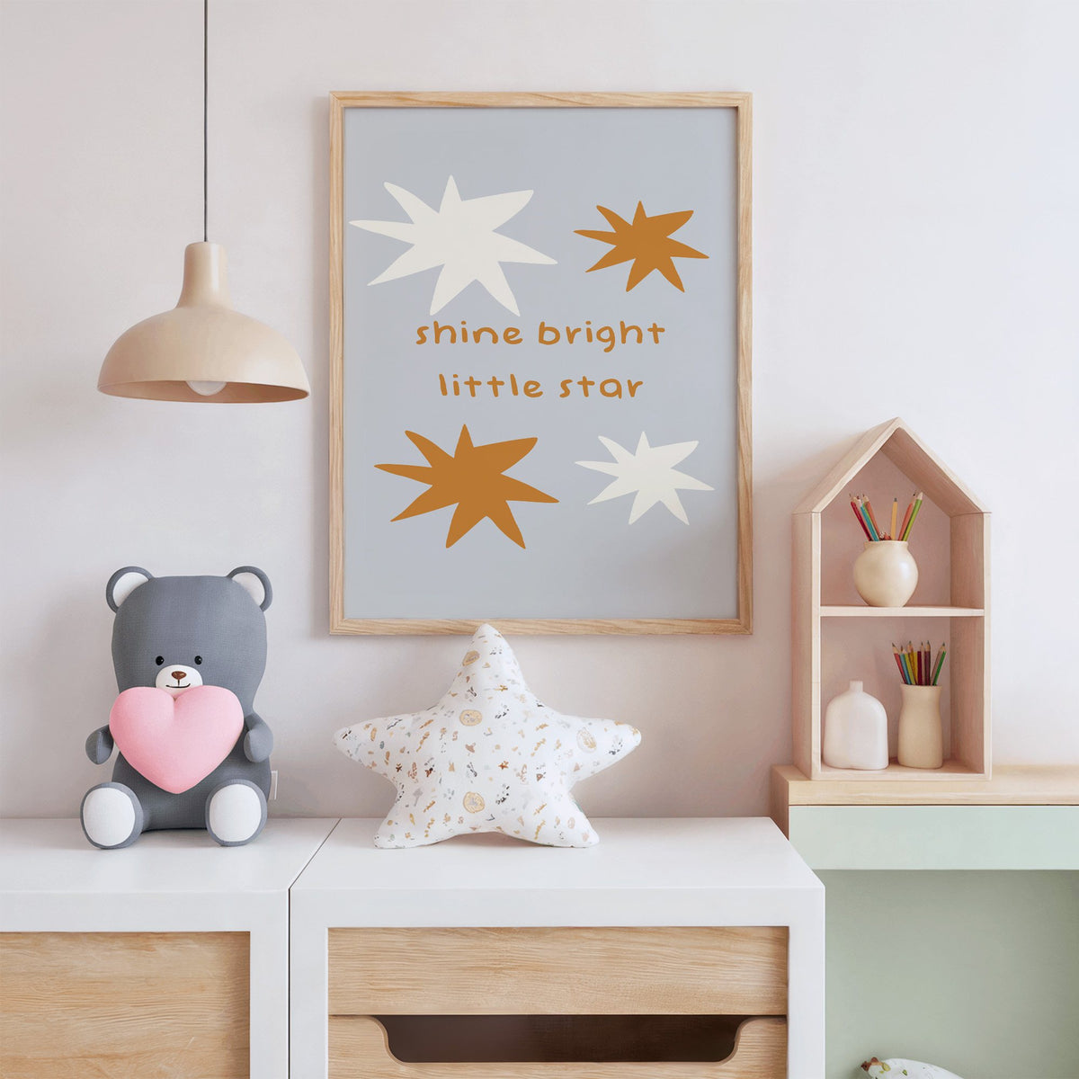 Shine bright little star nursery print in an oak frame above a white dresser with a star pillow and house shelf