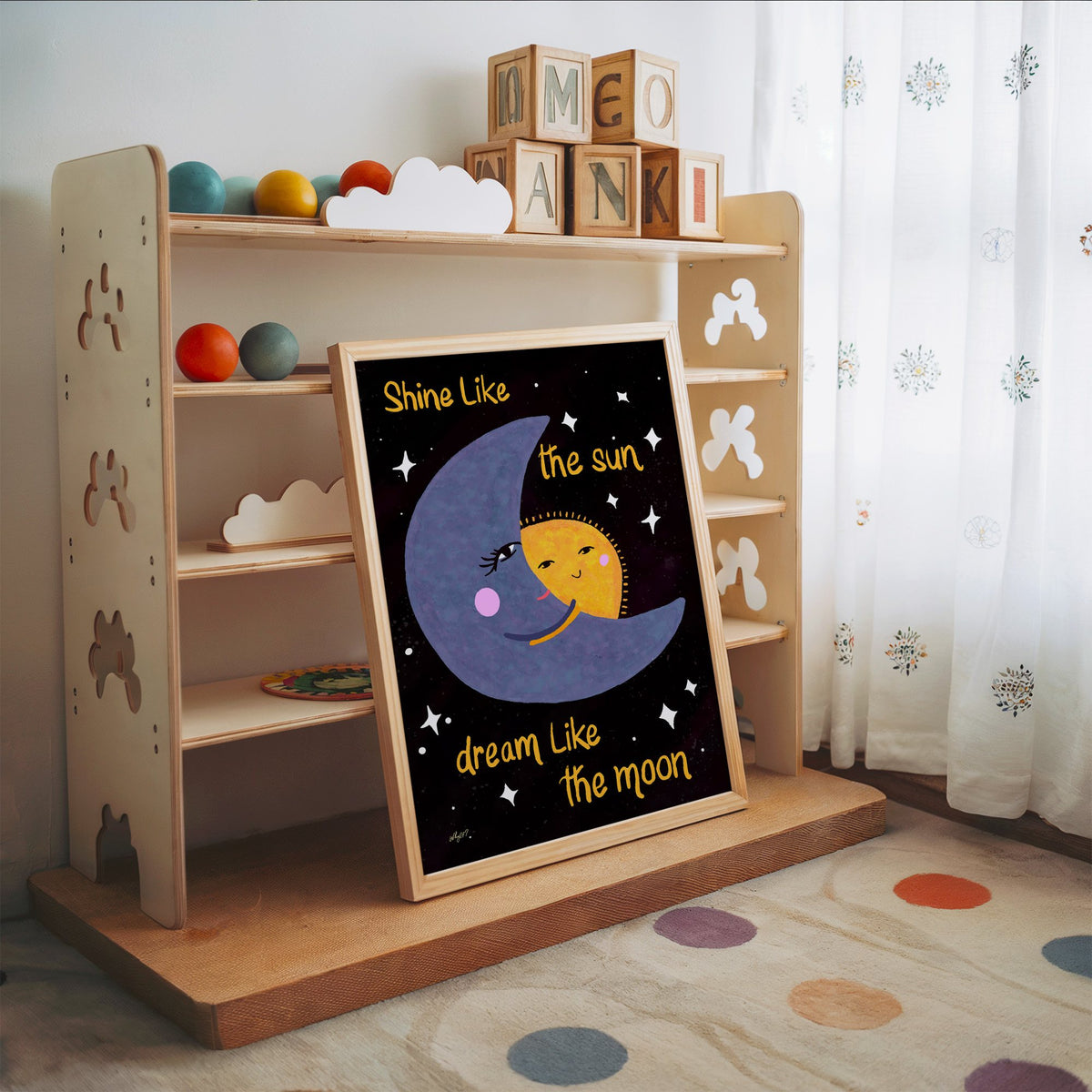 Moon hugging sun quote nursery print in an oak frame leaning on a toy shelf with wooden letter blocks