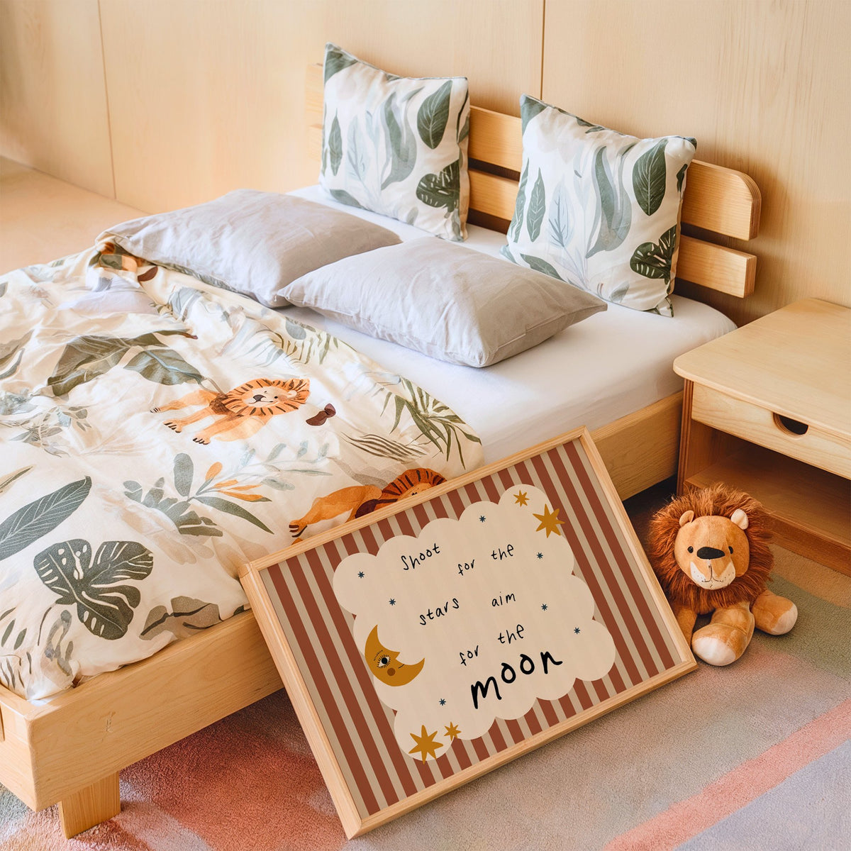 Landscape shoot for the stars moon nursery print in an oak frame leaning on a kids bed by a lion plush
