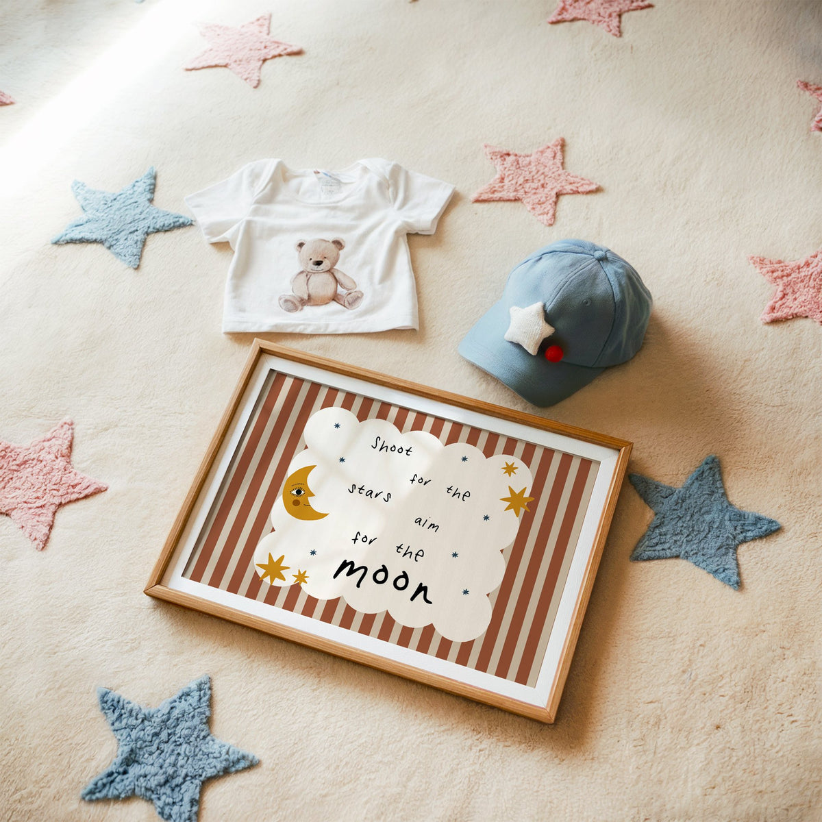 Landscape shoot for the stars moon nursery print in a matted oak frame on a star rug with a baby tee
