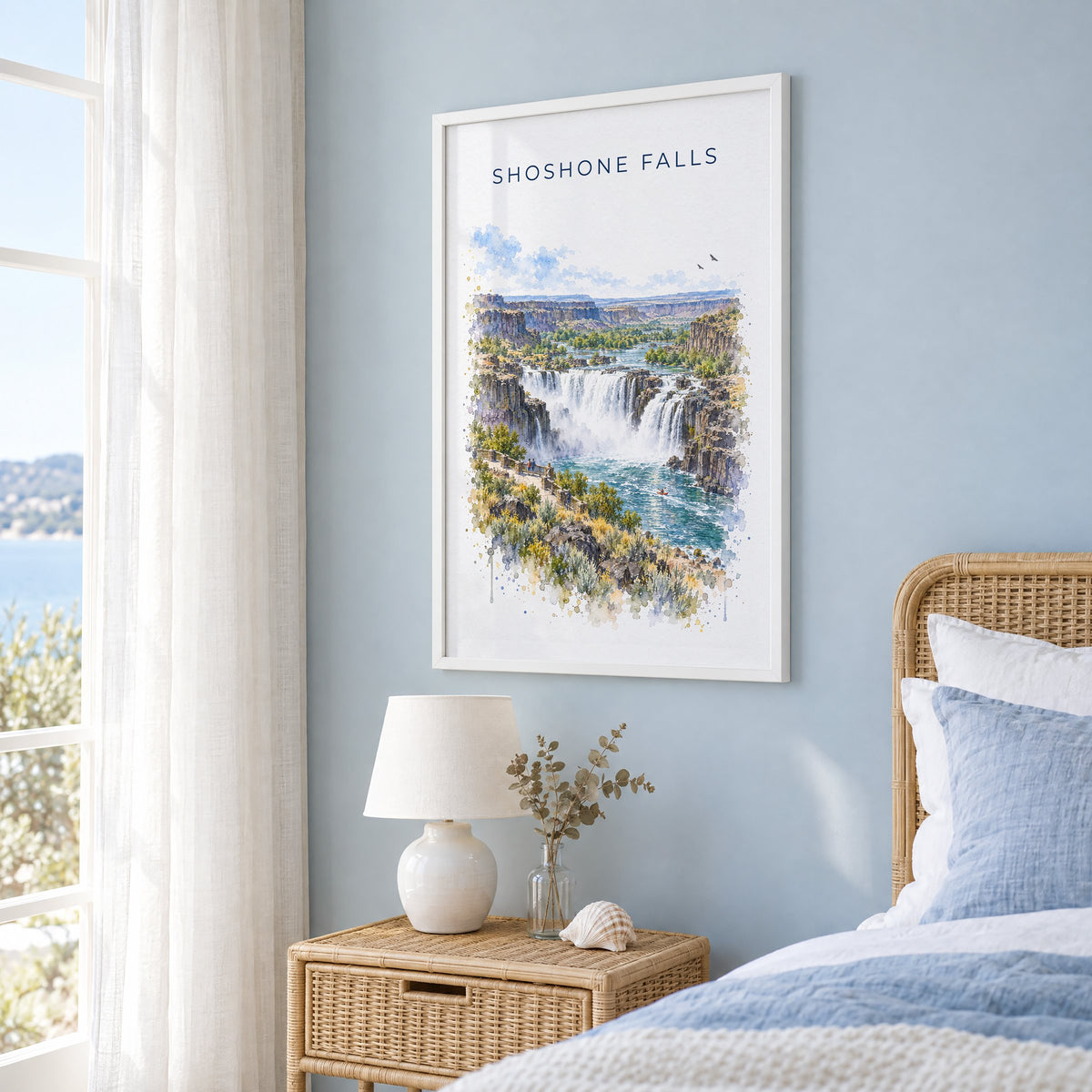 Shoshone Falls watercolor print in a white frame on a pale blue wall beside a rattan bed in a coastal bedroom