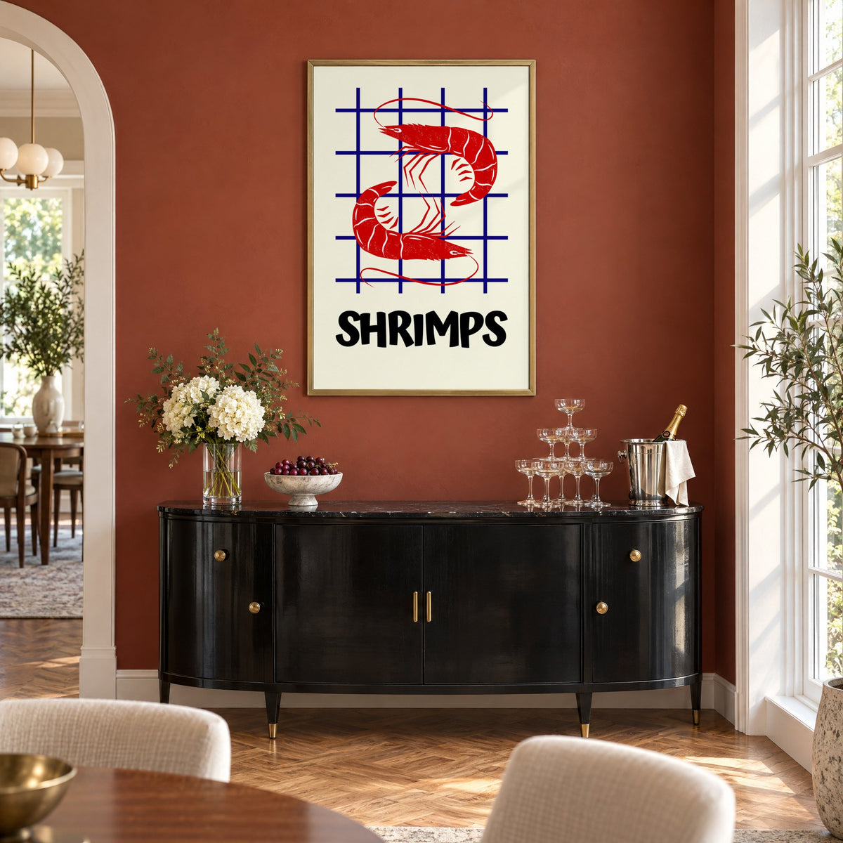 SHRIMPS red and blue grid print in a brass frame on a terracotta wall above a black buffet with a champagne tower