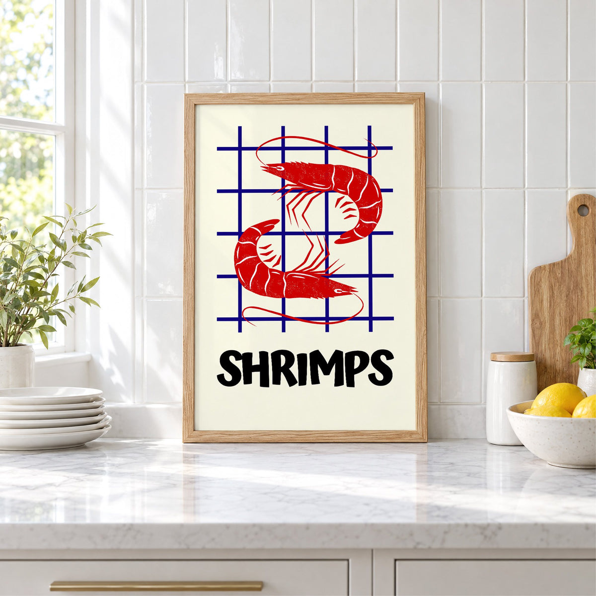 SHRIMPS red and blue grid print in an oak frame leaning on a marble counter by white tiles and lemons