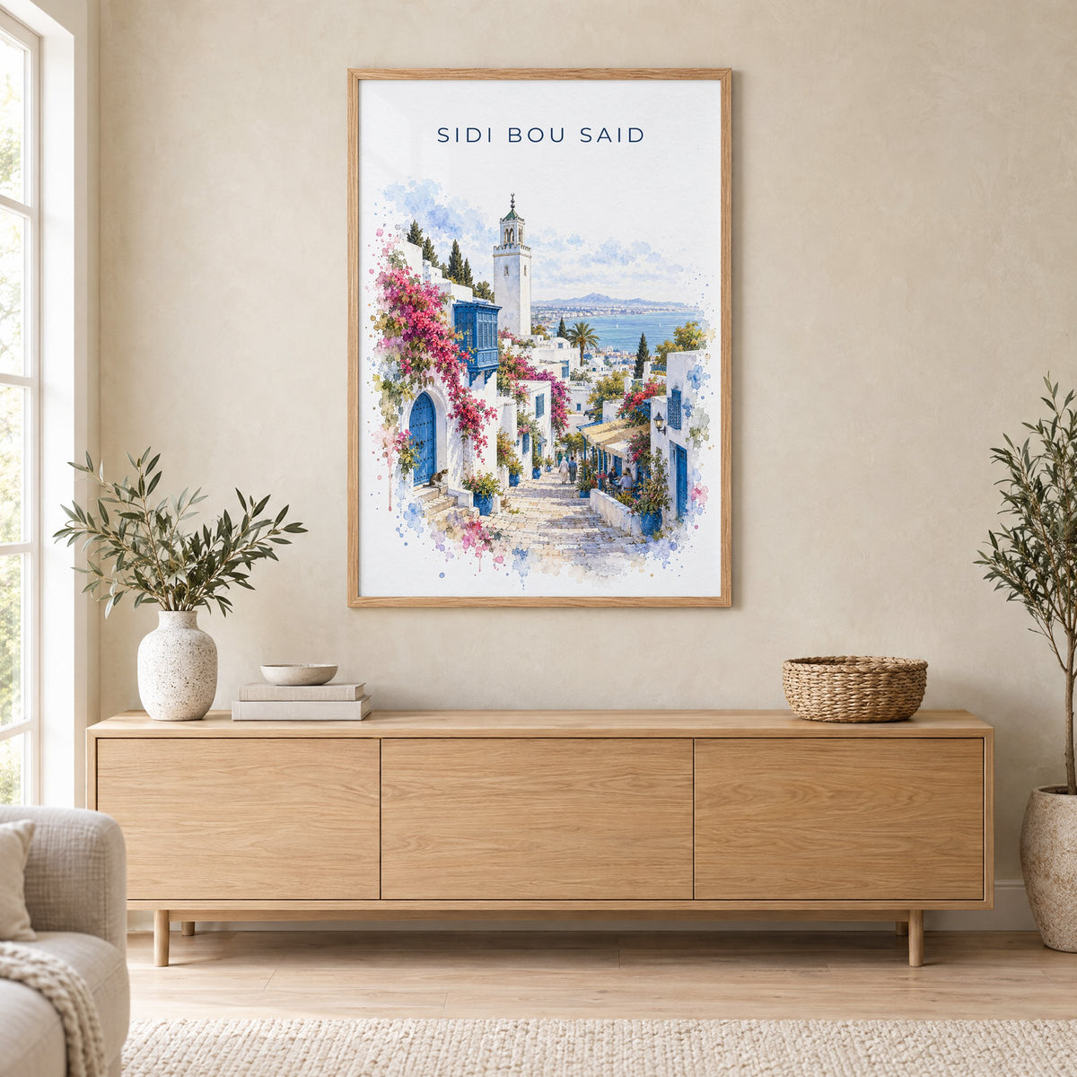 Sidi Bou Said watercolor print in an oak frame above a light wood sideboard in a Scandinavian living room
