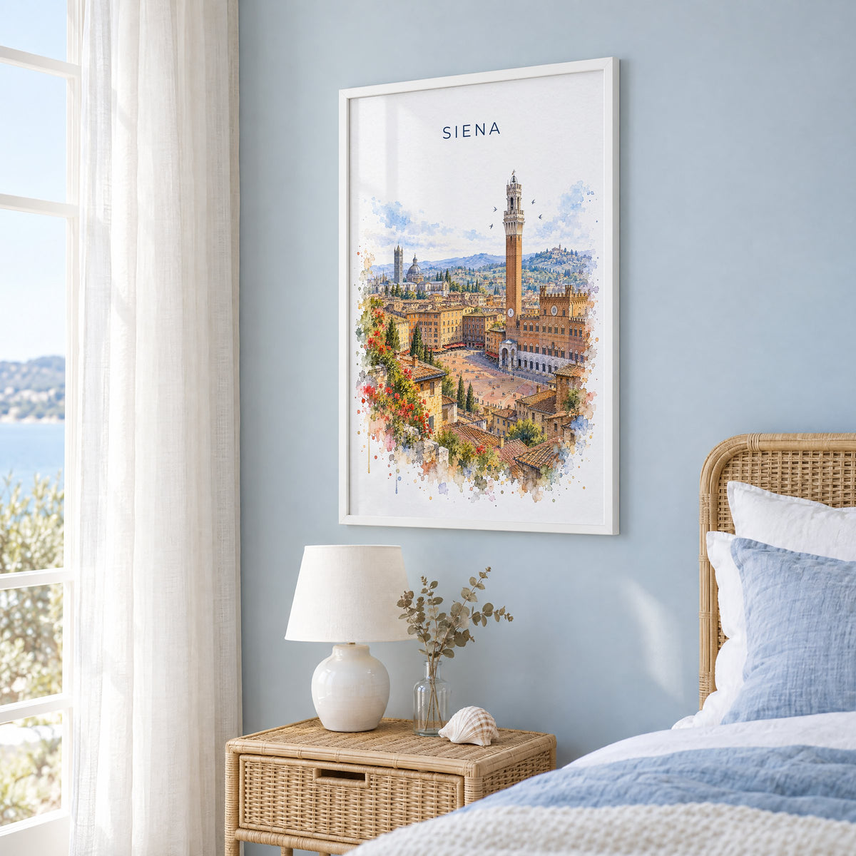 Siena watercolor print in a white frame on a pale blue wall beside a rattan bed in a coastal bedroom
