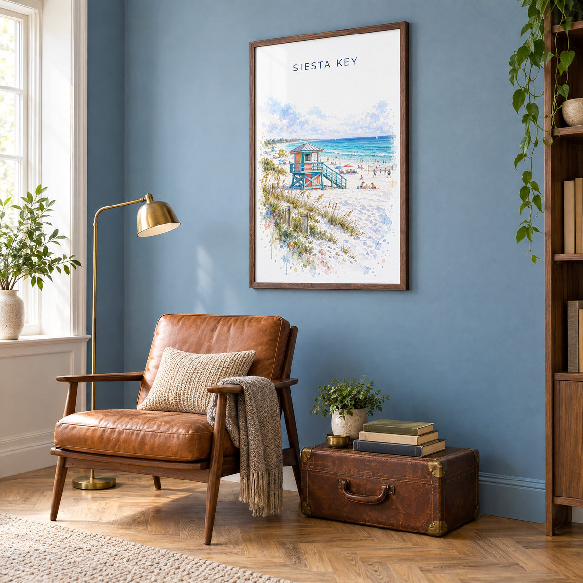 Siesta Key watercolor print in a walnut frame on a blue wall above a leather armchair in a reading nook