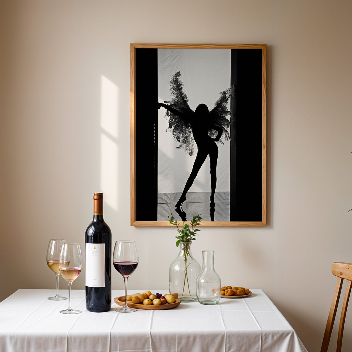 Backlit figure with feather wings in a doorway print in an oak frame above a table set with red wine and glasses