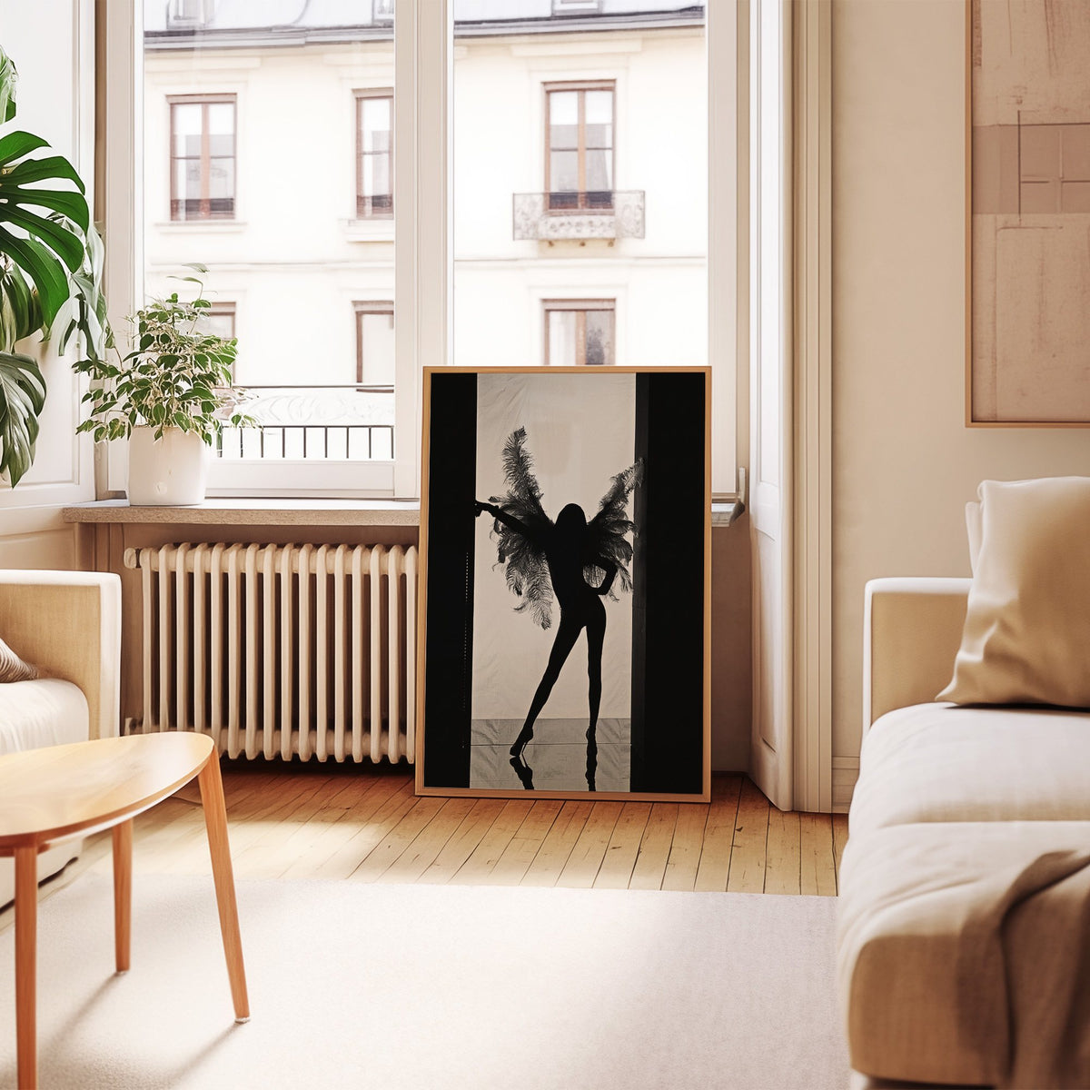 Backlit figure with feather wings in a doorway print in an oak frame leaning by a French window in a living room