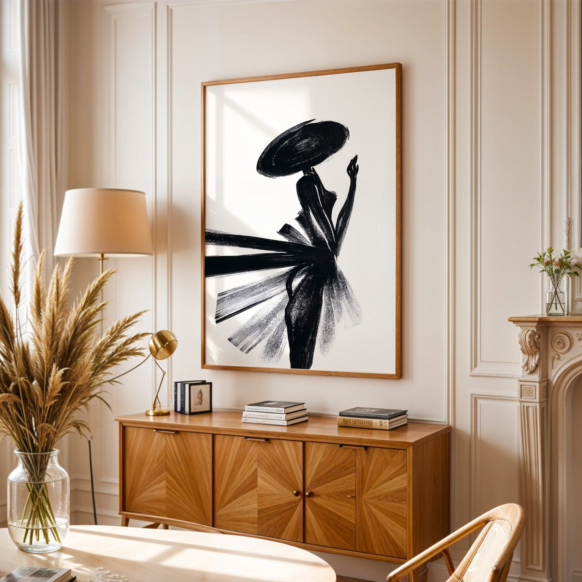 Woman in wide hat with fanned brushstroke skirt print in an oak frame above a sunburst wood sideboard with pampas grass