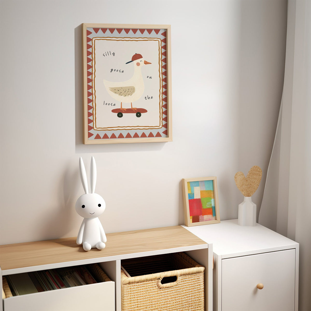 Silly goose on the loose nursery print in an oak frame above a kids cubby shelf with a woven basket and bunny lamp