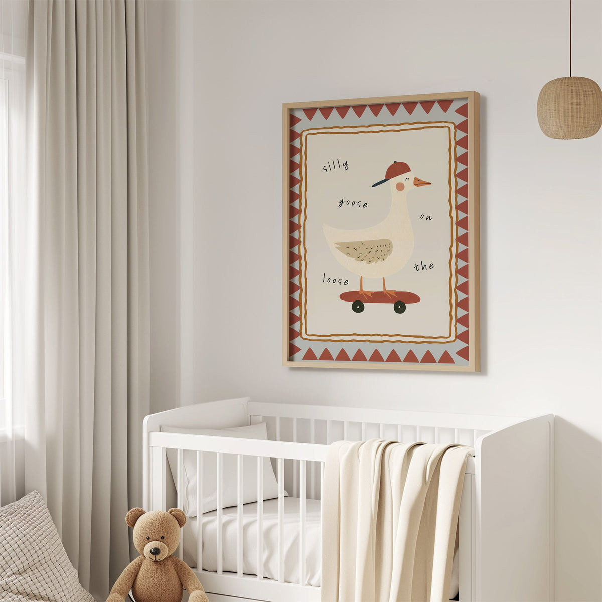 Silly goose on the loose nursery print in an oak frame above a white crib with a teddy bear
