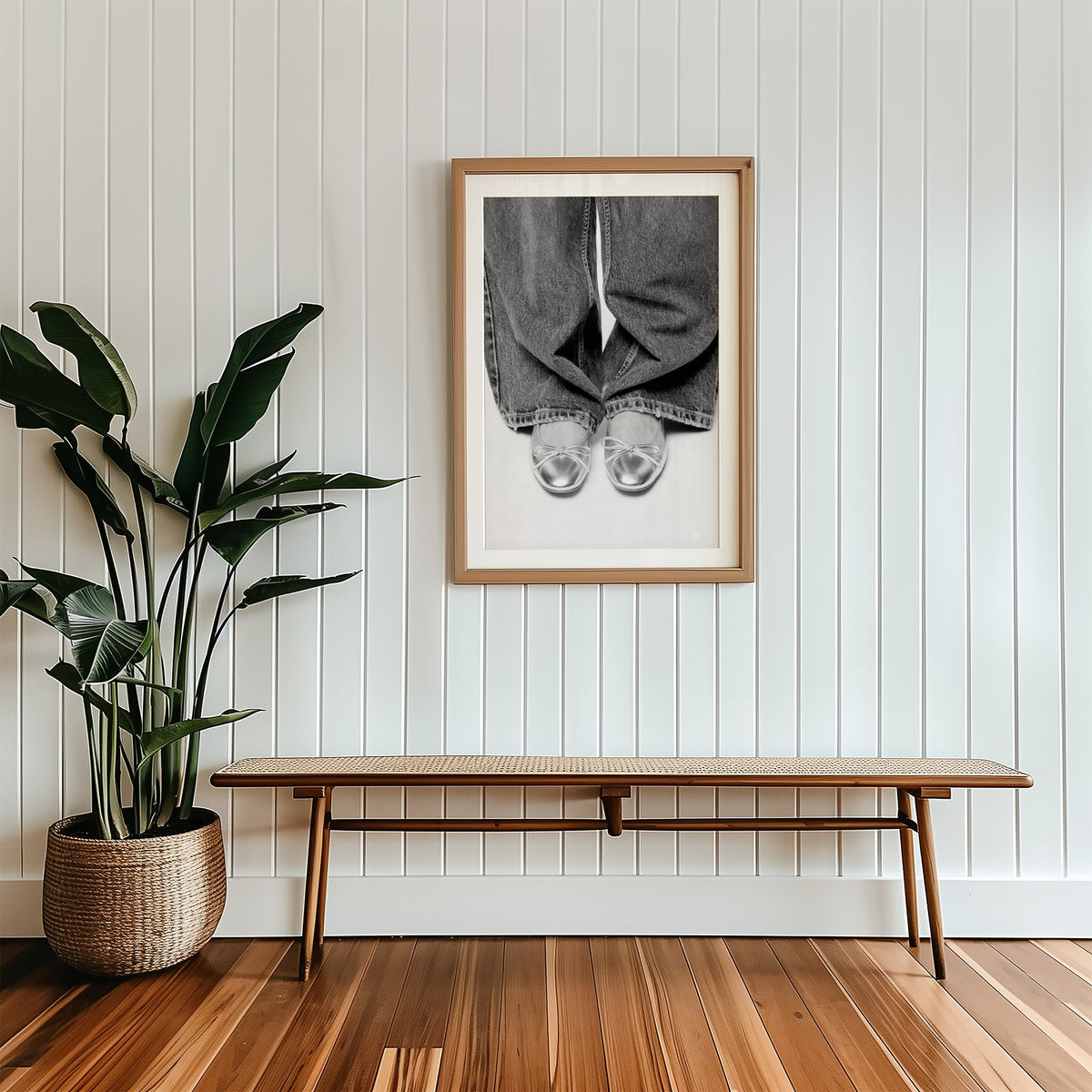Silver ballet flats under wide-leg jeans print in a wood frame with a white mat above a cane bench