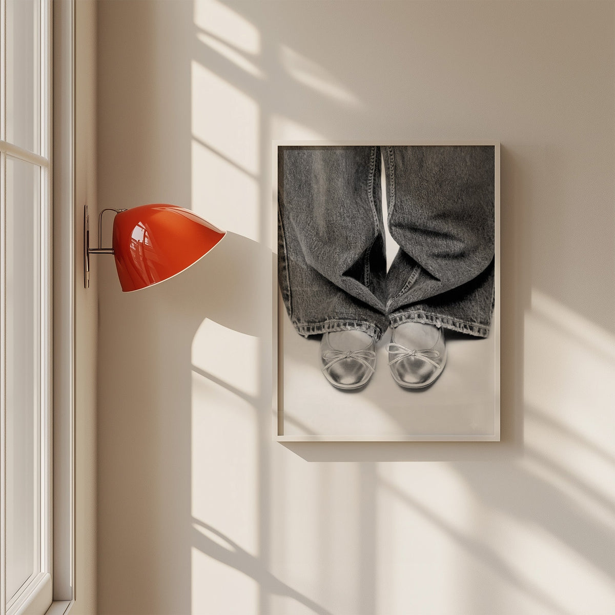 Silver ballet flats under wide-leg jeans print in a white frame on a sunlit wall beside a red sconce