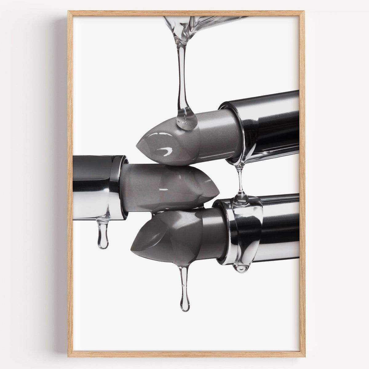 Silver lipsticks with clear gel drips print in a light oak frame on a plain white wall