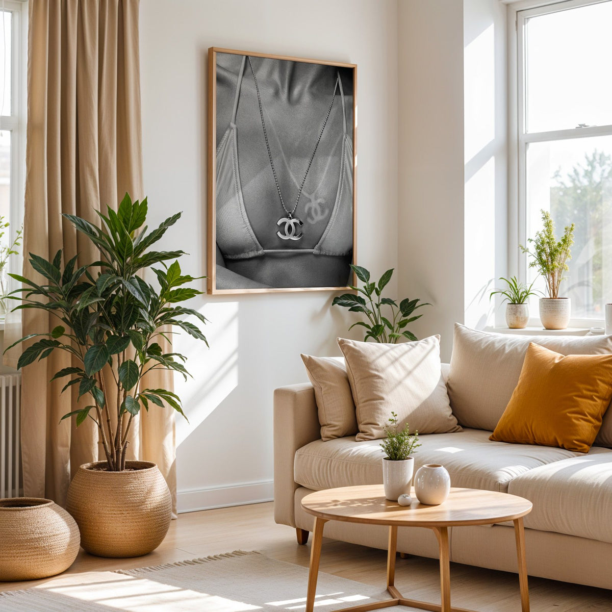 Close-up of logo pendant necklace and bikini tan line print in an oak frame above a cream sofa beside woven planters