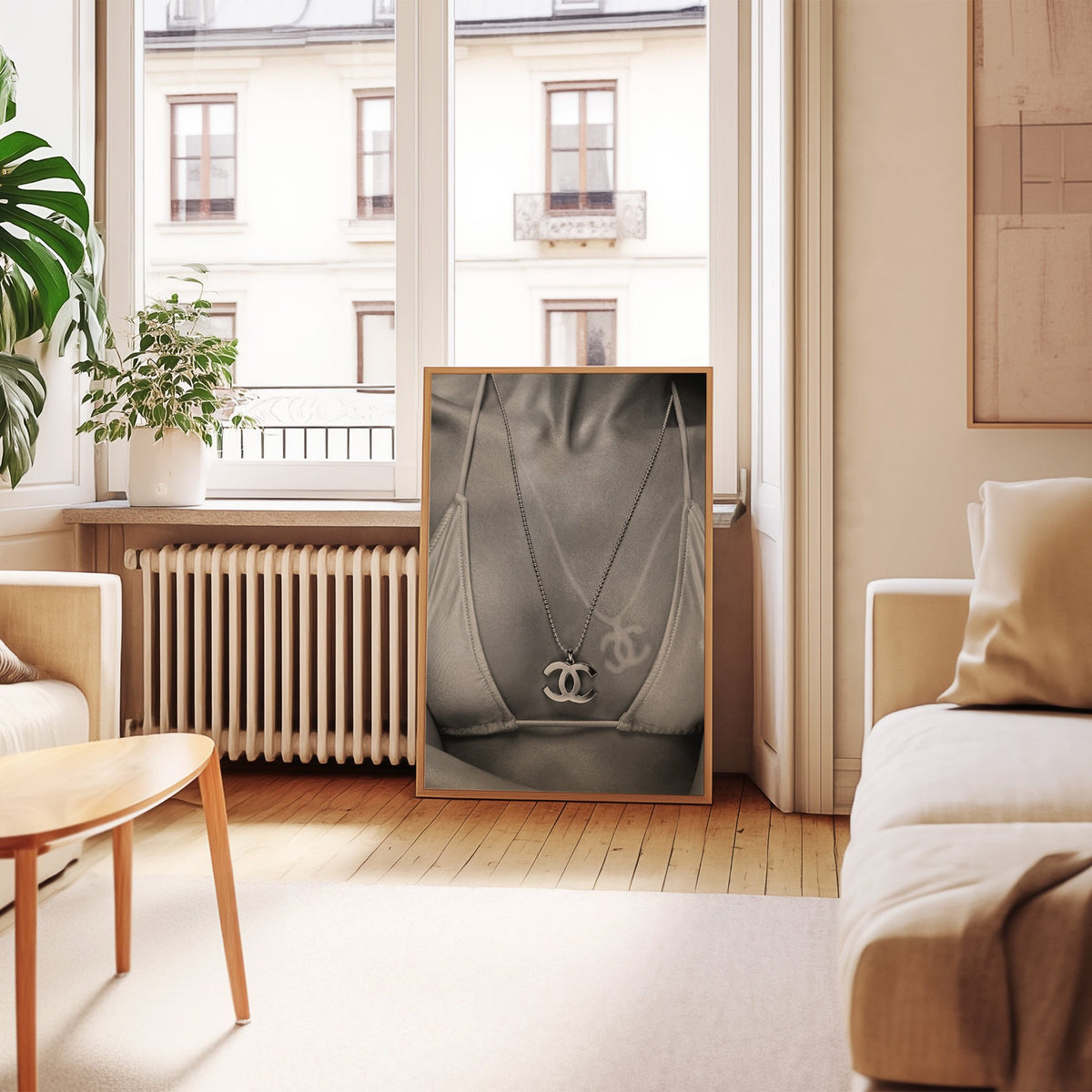 Close-up of logo pendant necklace and bikini tan line print in an oak frame leaning by a French window in a living room