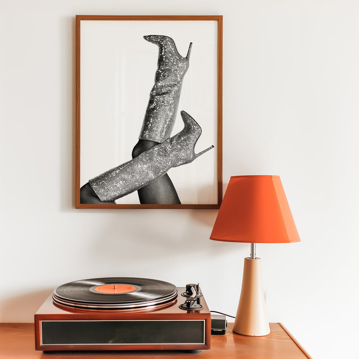 Silver sequin knee-high stiletto boots print in a walnut frame above a record player and orange lamp