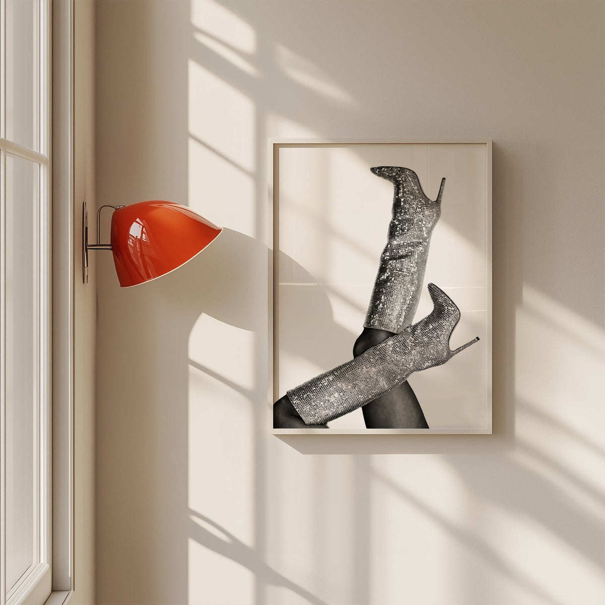 Silver sequin knee-high stiletto boots print in a white frame on a sunlit wall beside a red sconce