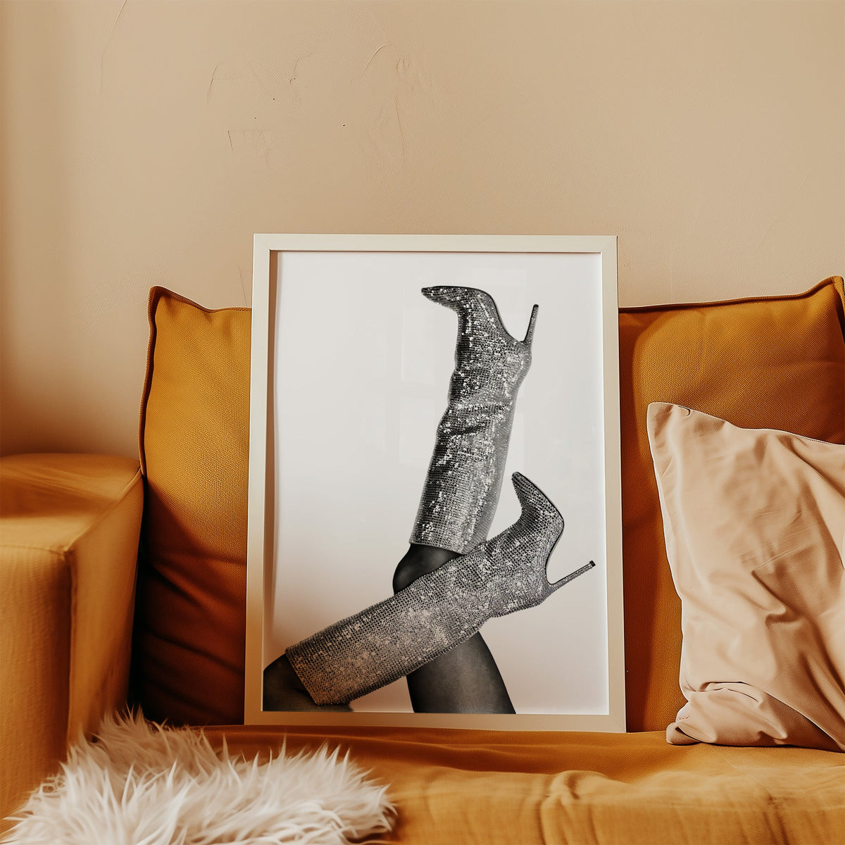 Silver sequin knee-high stiletto boots print in a white frame leaning on a mustard velvet sofa