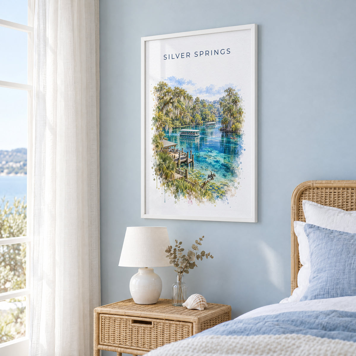 Silver Springs State Park watercolor print in a white frame on a pale blue wall beside a rattan bed in a coastal bedroom