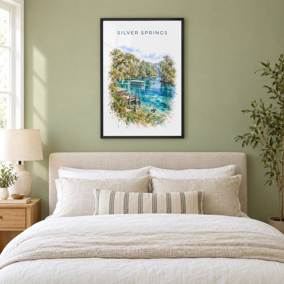 Silver Springs State Park watercolor print in a black frame above an upholstered headboard in a sage green bedroom