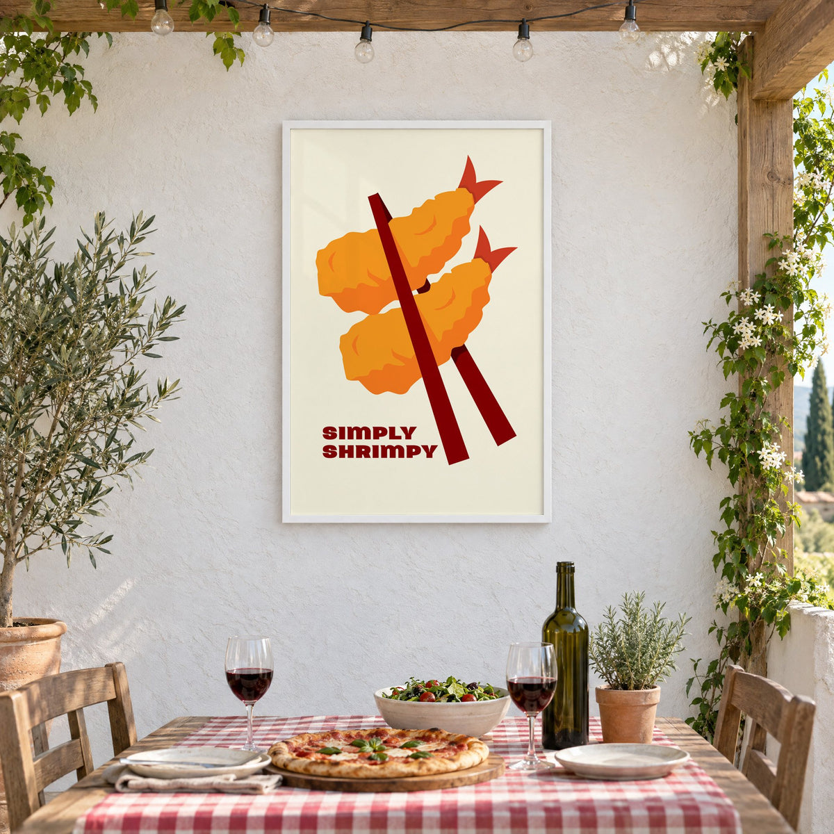 SIMPLY SHRIMPY tempura shrimp chopsticks print in a white frame on a stucco wall above a checked-cloth table with pizza and red wine