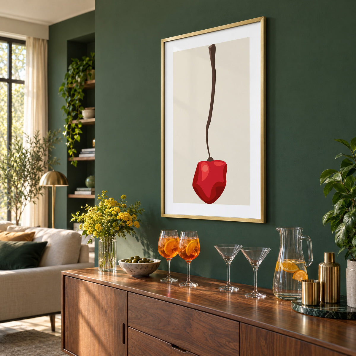 Single red cherry long stem minimalist print in a brass frame on a bottle green wall above a sideboard with spritz and martini glasses, seen at an angle