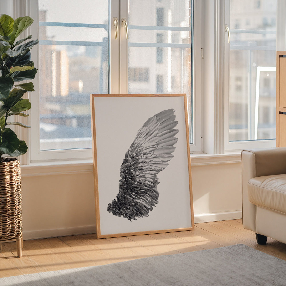 Single silver metallic wing on white print in an oak frame leaning on the floor beside a fiddle leaf fig