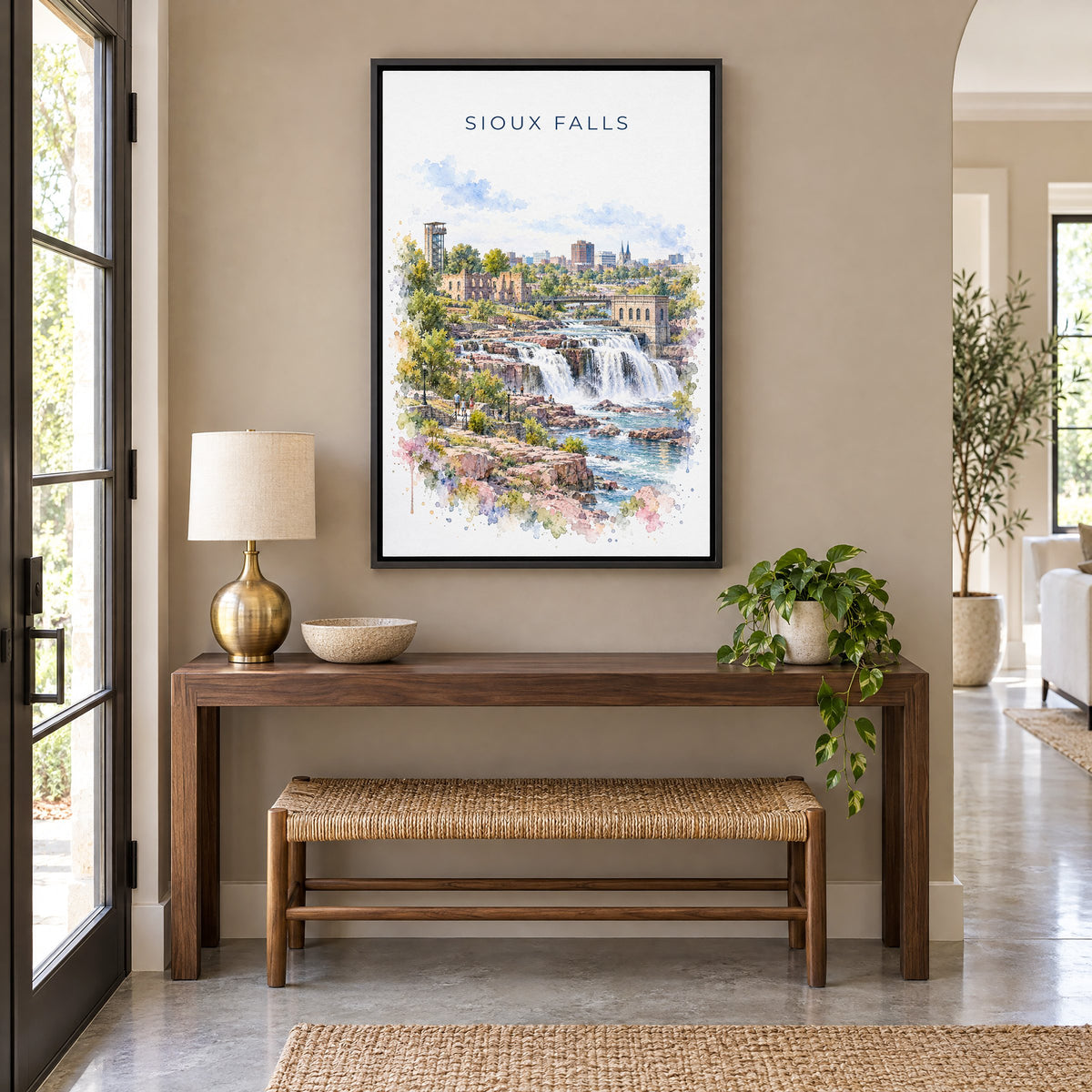 Sioux Falls watercolor print as a black floater canvas above a walnut console and woven bench in an entryway
