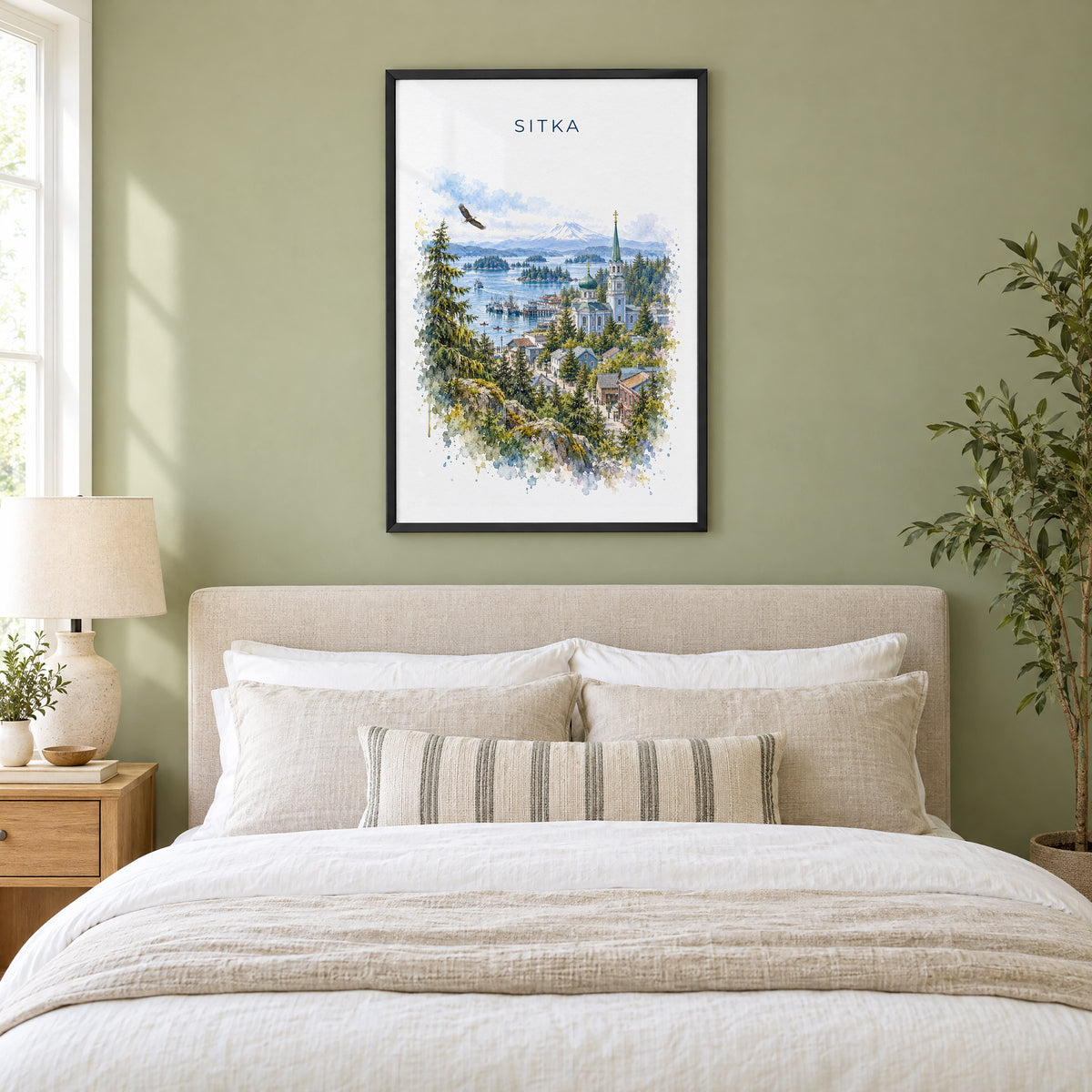 Sitka, Alaska watercolor print in a black frame above an upholstered headboard in a sage green bedroom