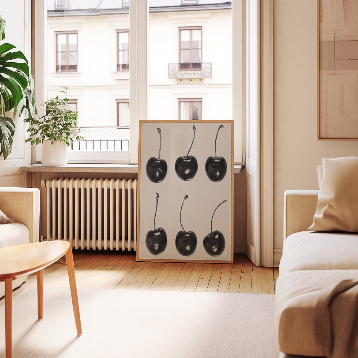 Six glossy black cherries in a grid on gray print in an oak frame leaning by a French window in a living room