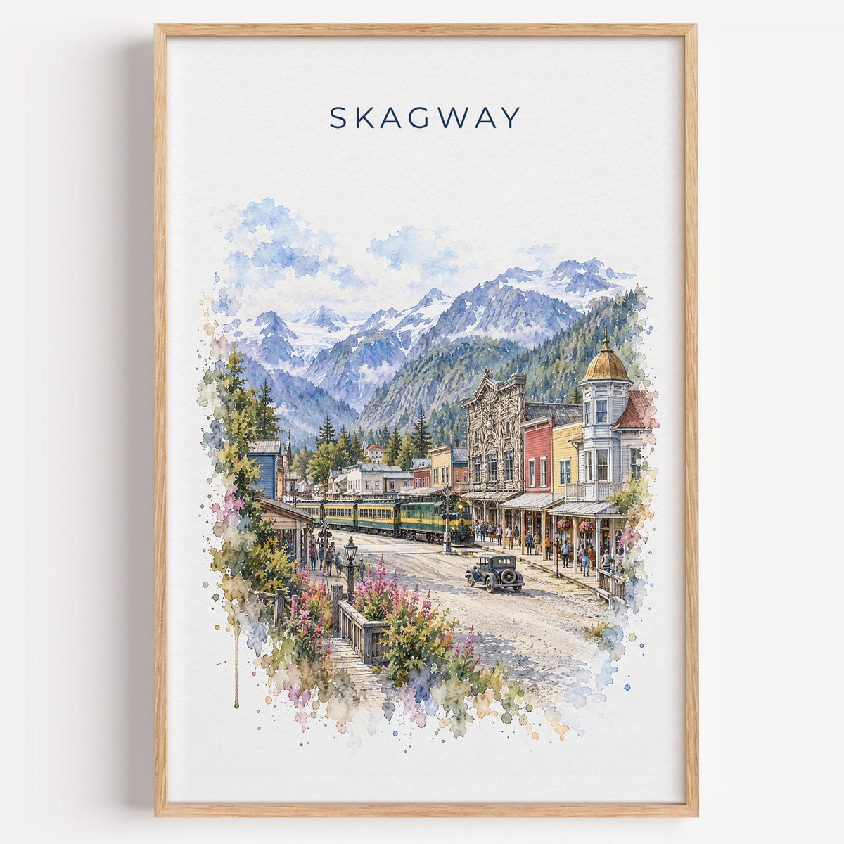 Skagway, Alaska watercolor print in a light oak frame on a plain white wall