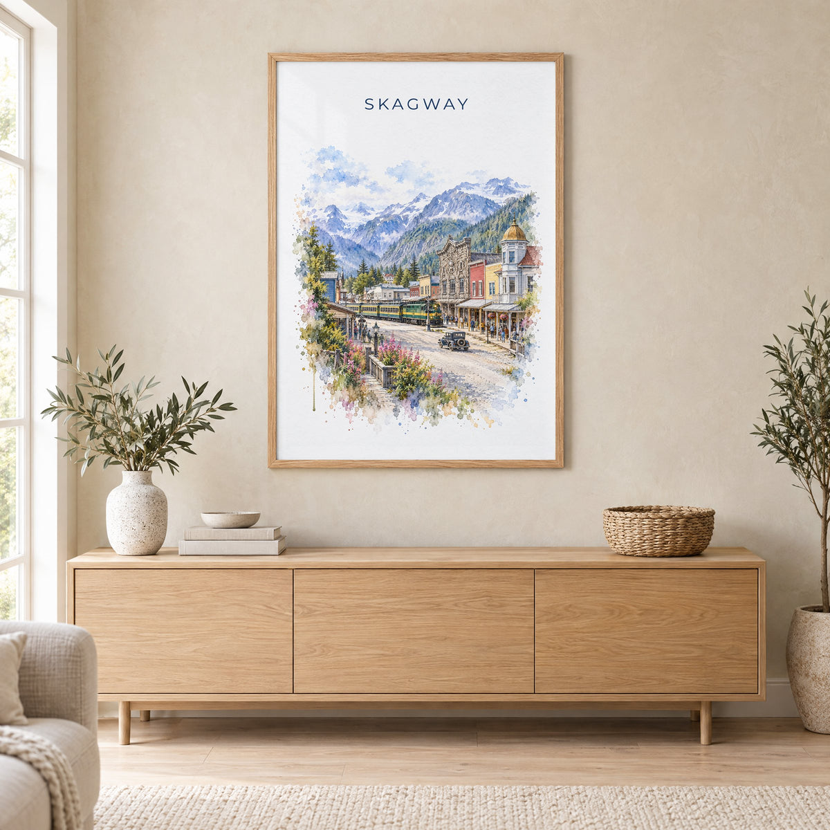 Skagway, Alaska watercolor print in an oak frame above a light wood sideboard in a Scandinavian living room