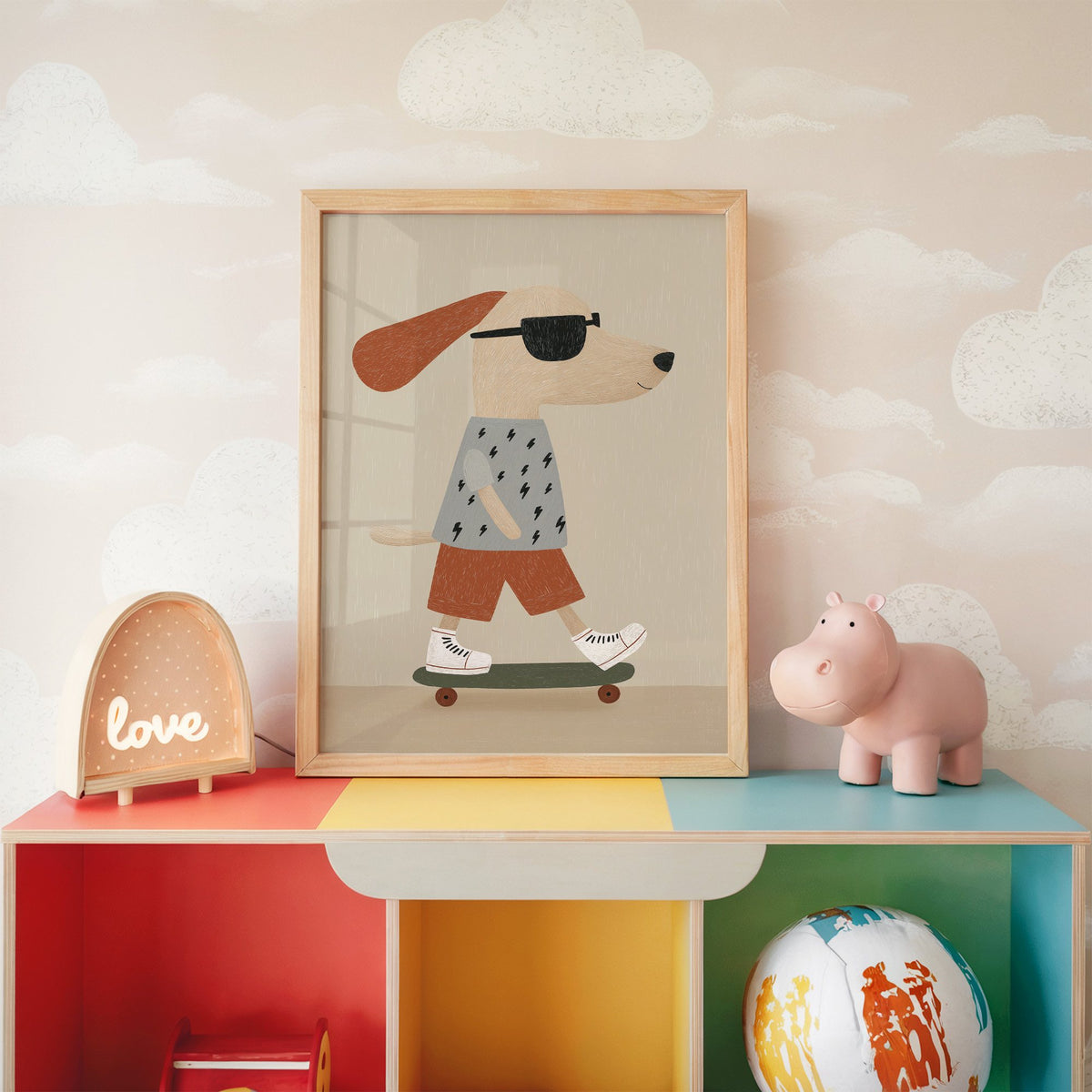 Skateboard dog lightning tee nursery print in an oak frame on a rainbow toy shelf against cloud wallpaper