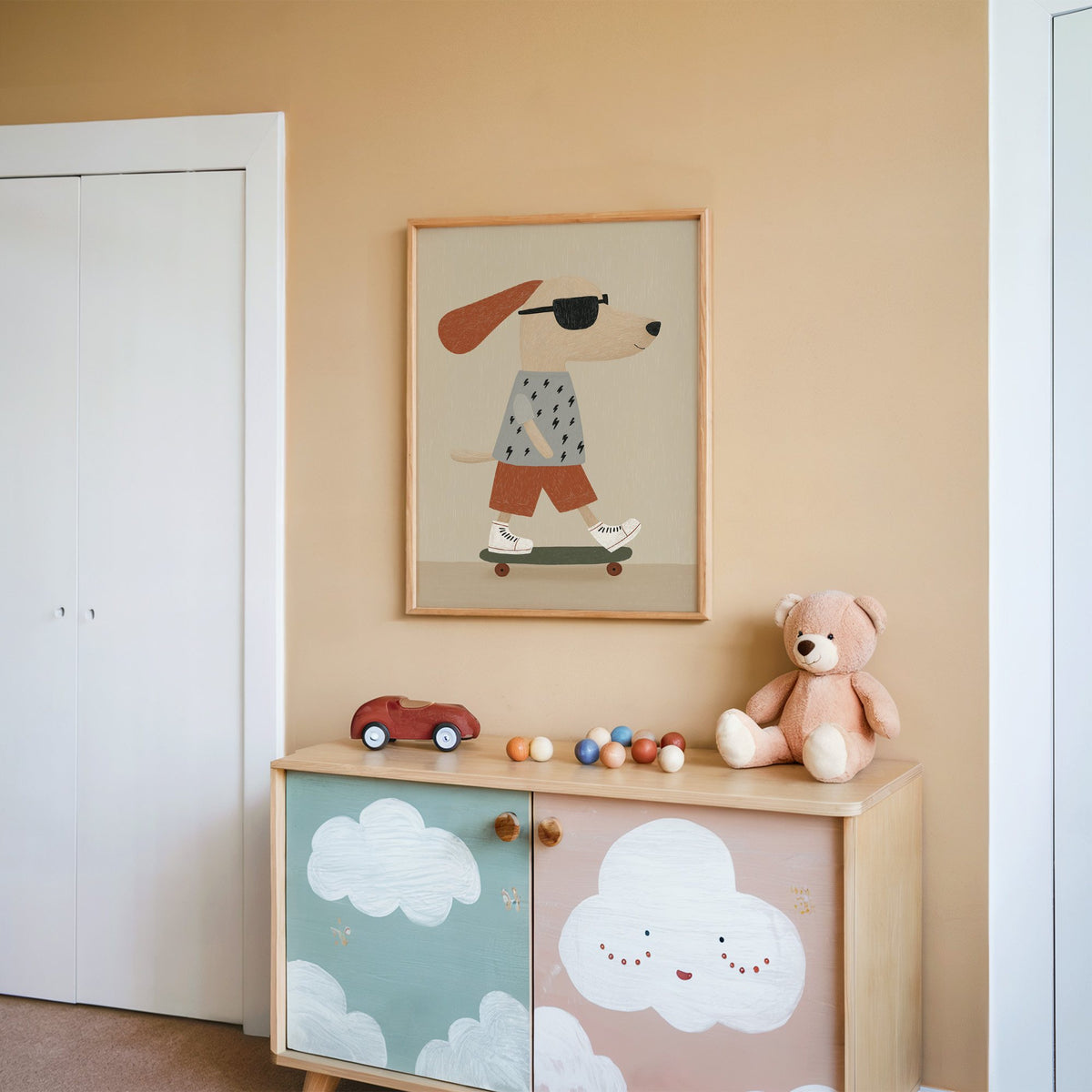 Skateboard dog lightning tee nursery print in an oak frame on a peach wall above a cloud-painted cabinet