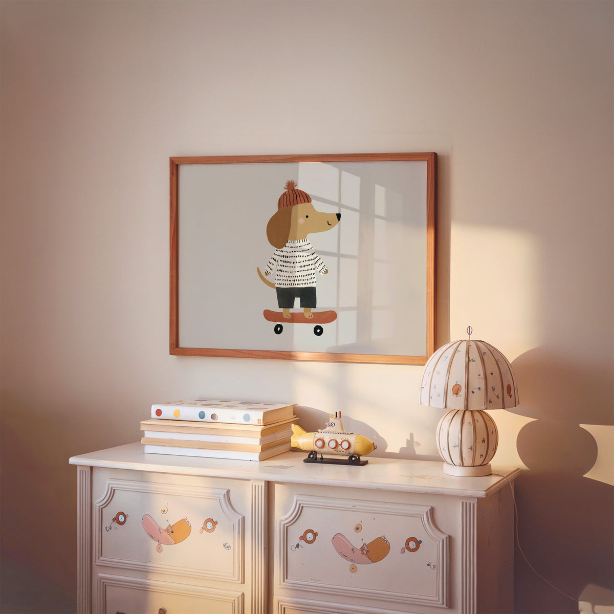 Landscape skateboard dog pompom beanie nursery print in a cherry wood frame above a painted dresser and lamp