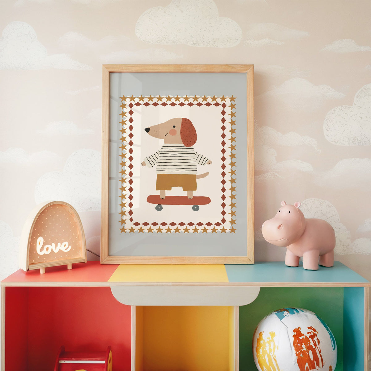 Skateboard dog star frame nursery print in an oak frame on a rainbow toy shelf against cloud wallpaper