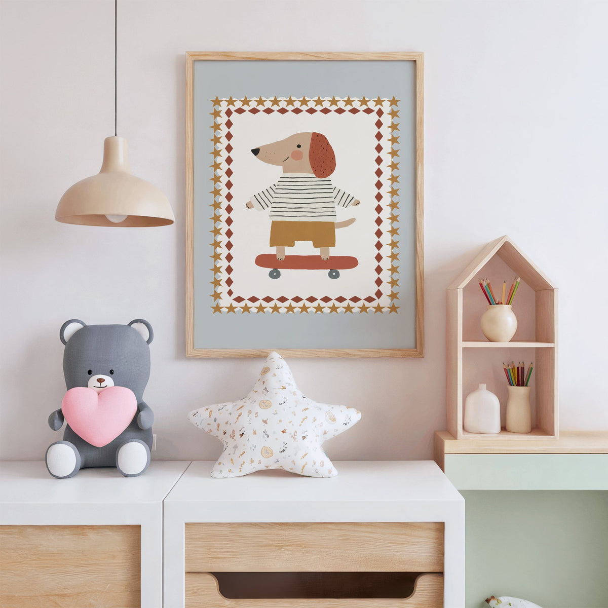 Skateboard dog star frame nursery print in an oak frame above a white dresser with a star pillow and house shelf