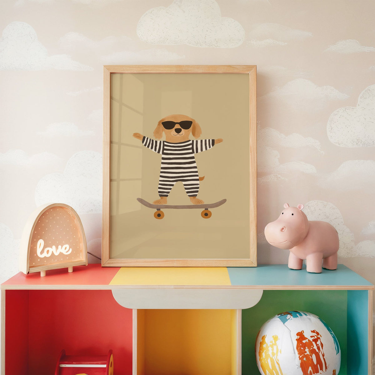 Skateboard dog striped onesie nursery print in an oak frame on a rainbow toy shelf against cloud wallpaper