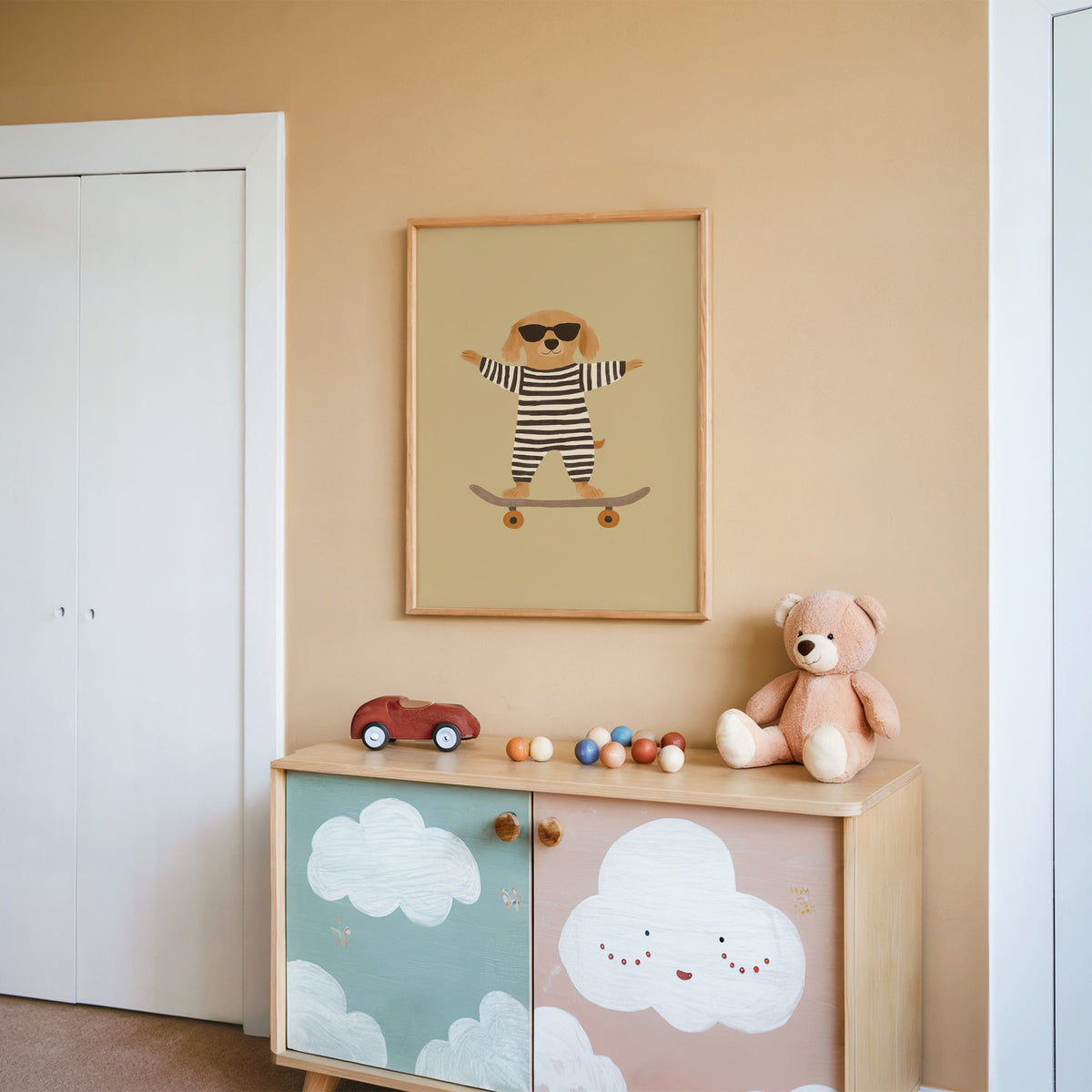 Skateboard dog striped onesie nursery print in an oak frame on a peach wall above a cloud-painted cabinet