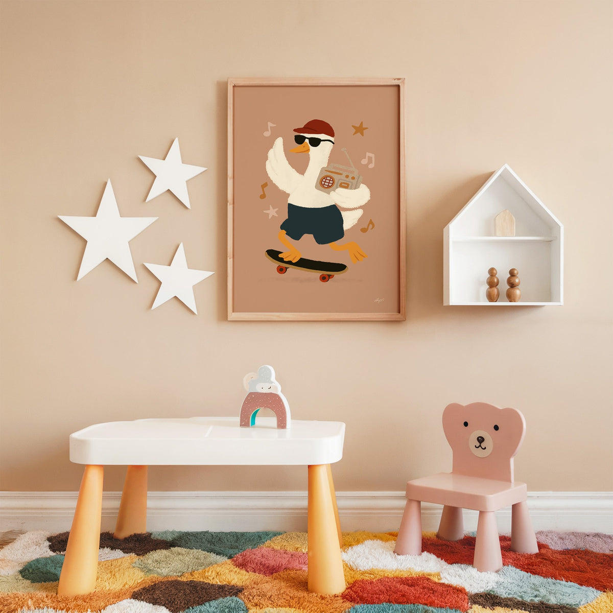 Goose on skateboard with boombox nursery print in an oak frame on a peach wall above a kids table with wall stars