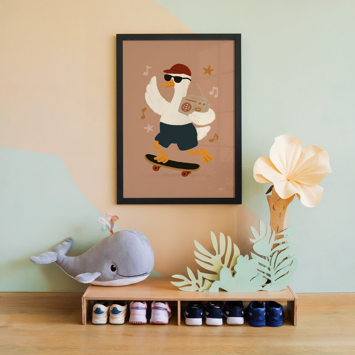 Goose on skateboard with boombox nursery print in a black frame on a mint and peach wall above a whale plush