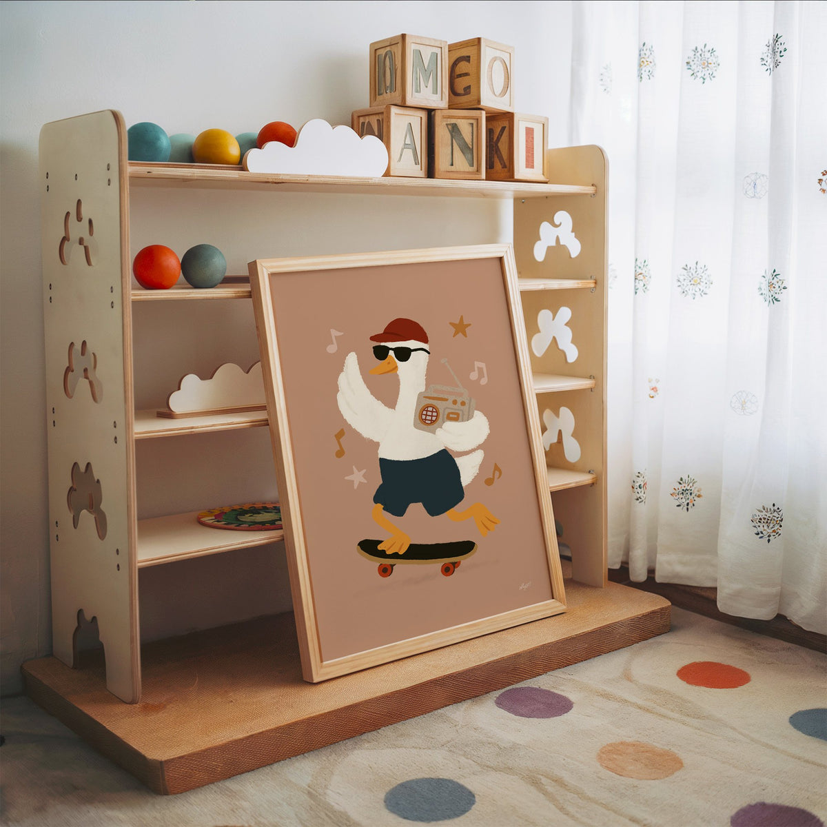 Goose on skateboard with boombox nursery print in an oak frame leaning on a toy shelf with wooden letter blocks