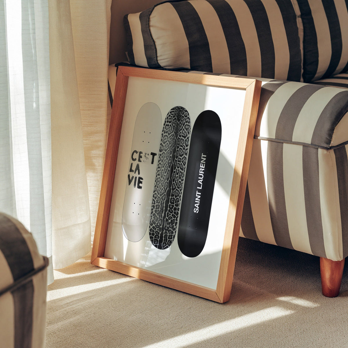 Three skateboards with leopard deck and lettering print in a pine frame leaning against a striped armchair
