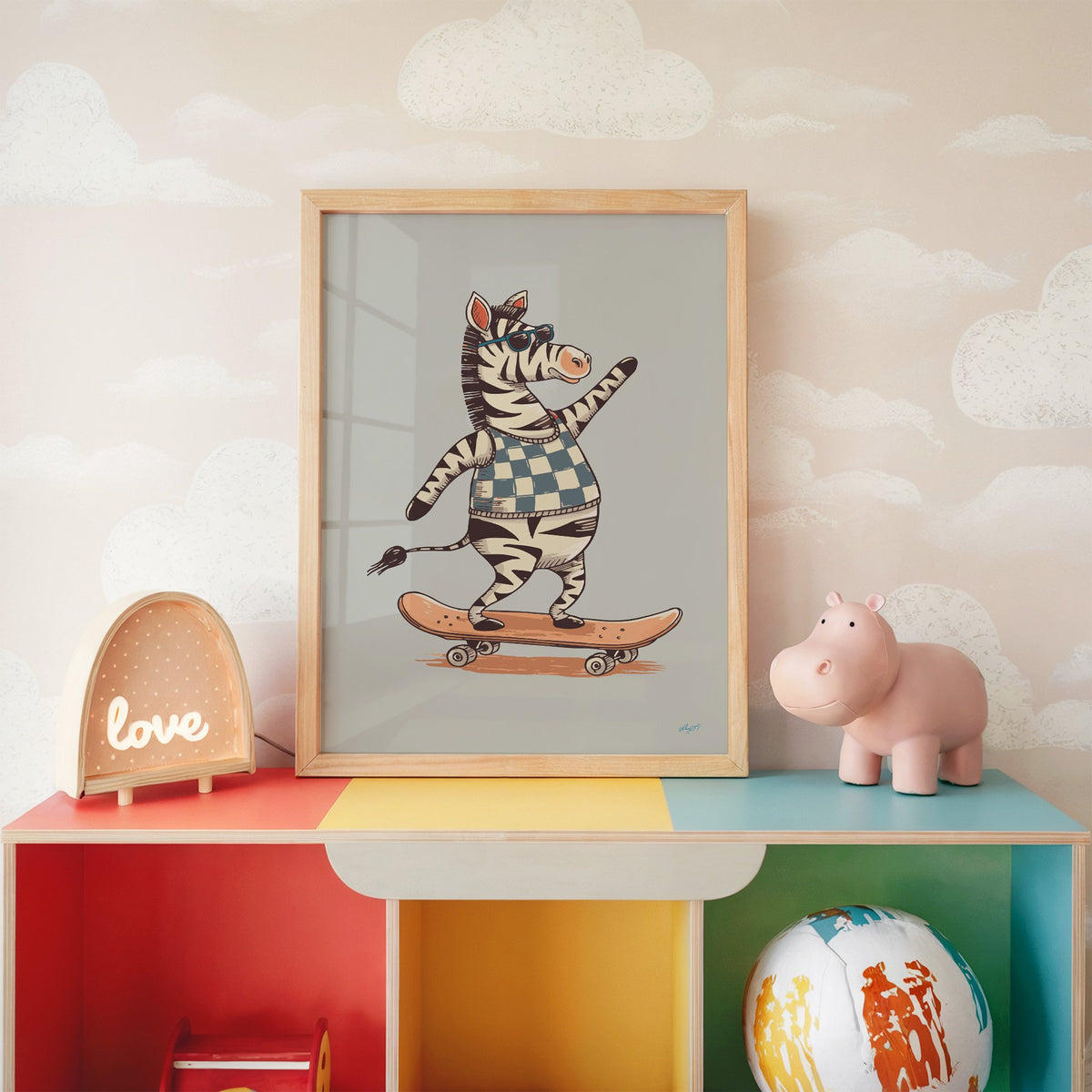 Zebra on orange skateboard nursery print in an oak frame on a rainbow toy shelf against cloud wallpaper