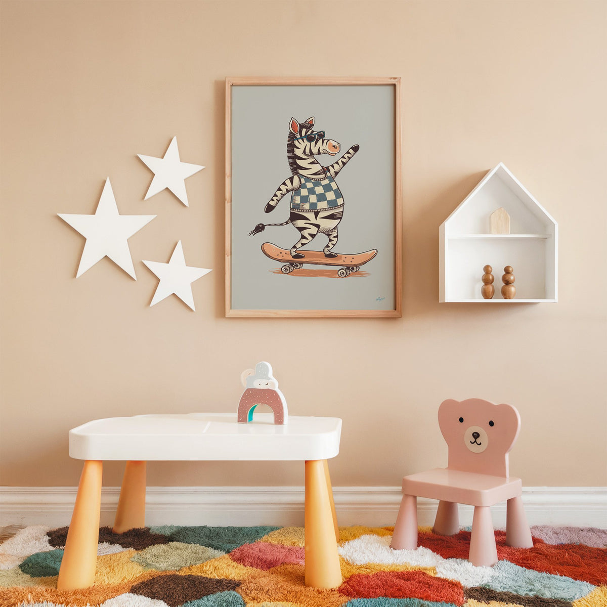 Zebra on orange skateboard nursery print in an oak frame on a peach wall above a kids table with wall stars