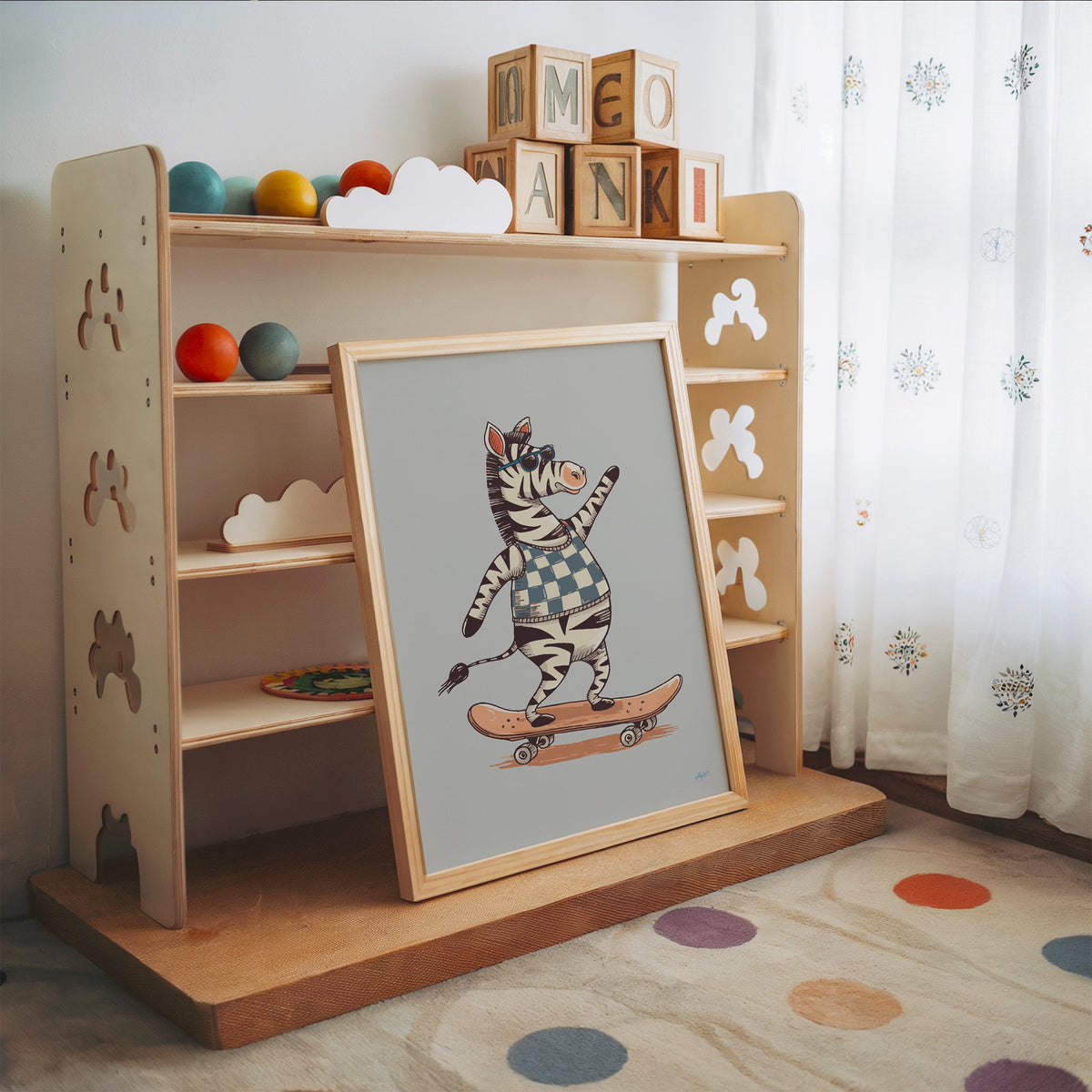 Zebra on orange skateboard nursery print in an oak frame leaning on a toy shelf with wooden letter blocks