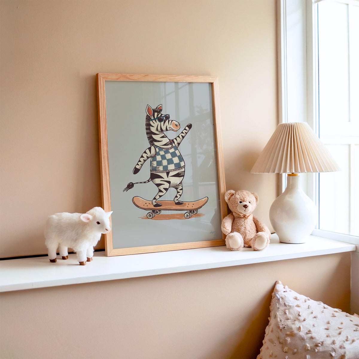 Zebra on orange skateboard nursery print in an oak frame on a window ledge with a toy lamb and teddy